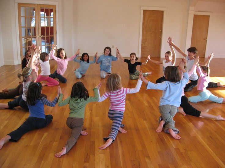 a group of children are doing yoga in an empty room with their arms raised up