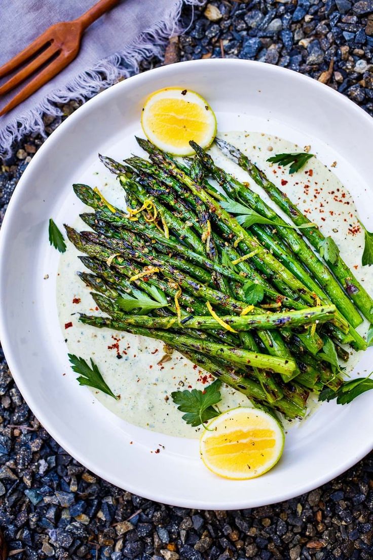 asparagus on a white plate with lemon wedges