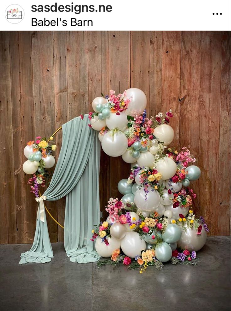 balloons and flowers are on display in front of a wooden wall