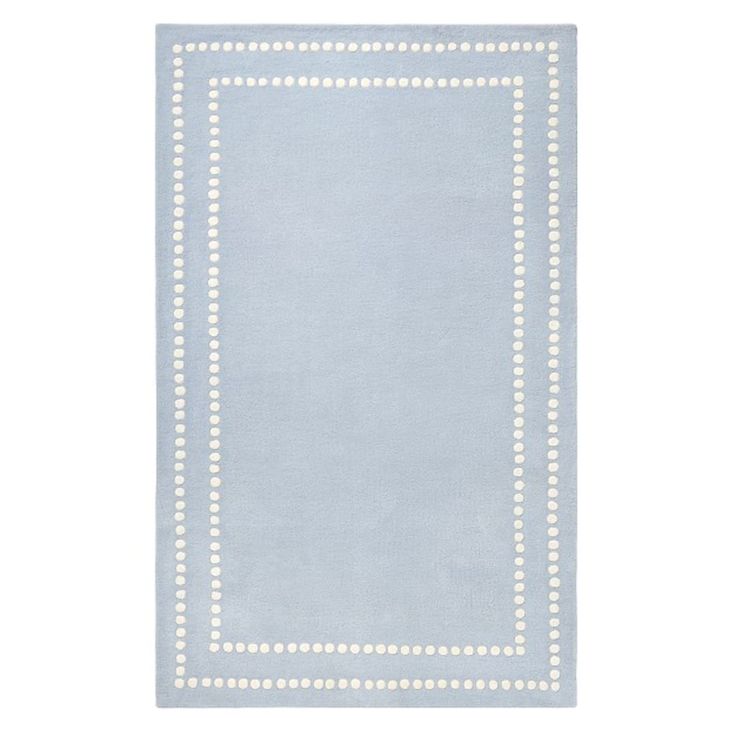 a light blue rug with white dots on the border and a square shape in the middle