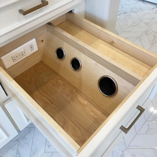 an open drawer in a white kitchen with drawers