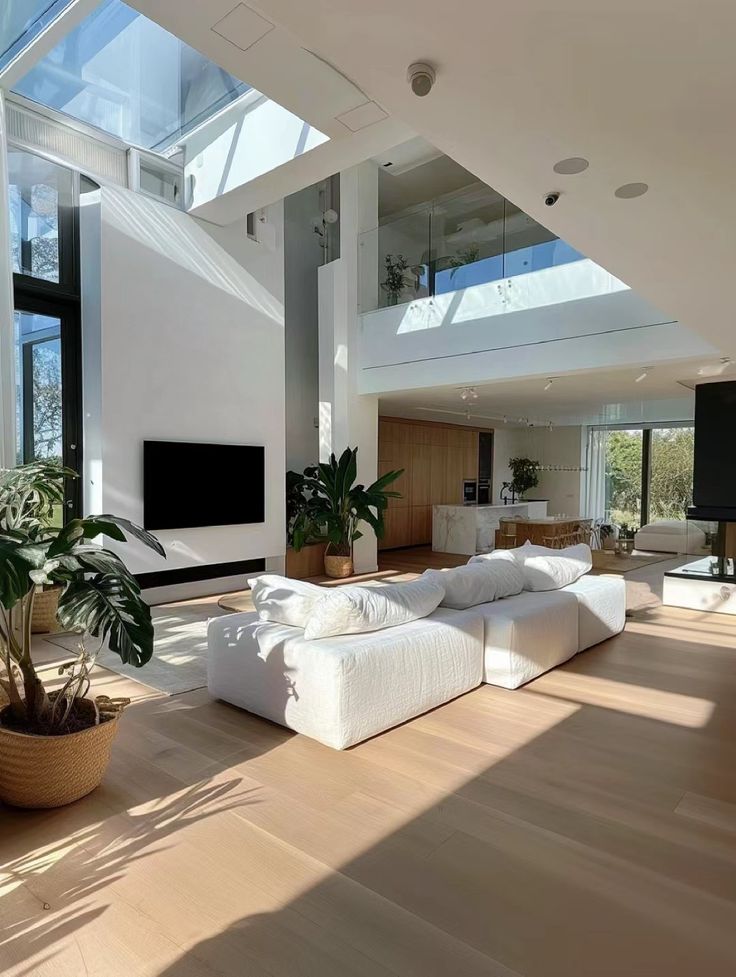 a living room filled with lots of white furniture and large windows over the top of it