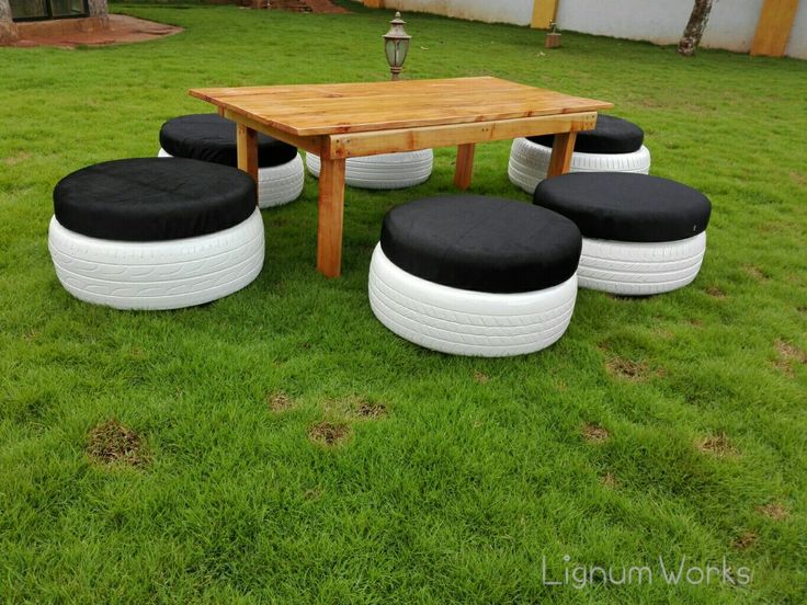 a wooden table with black cushions sitting on top of green grass