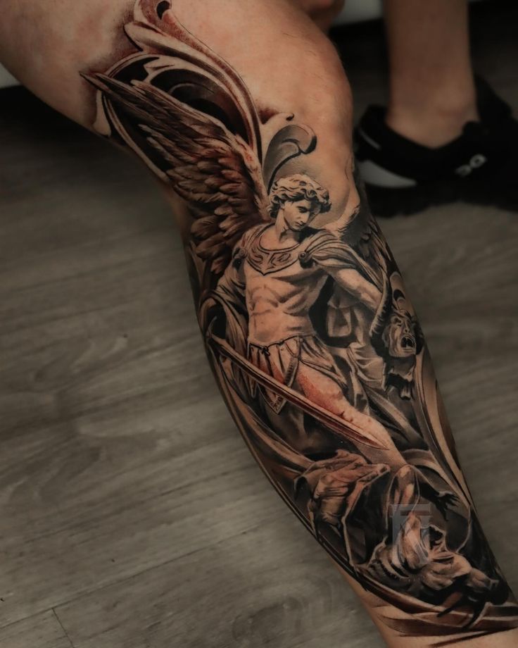 a man's leg with an angel and demon tattoo on the side of his arm