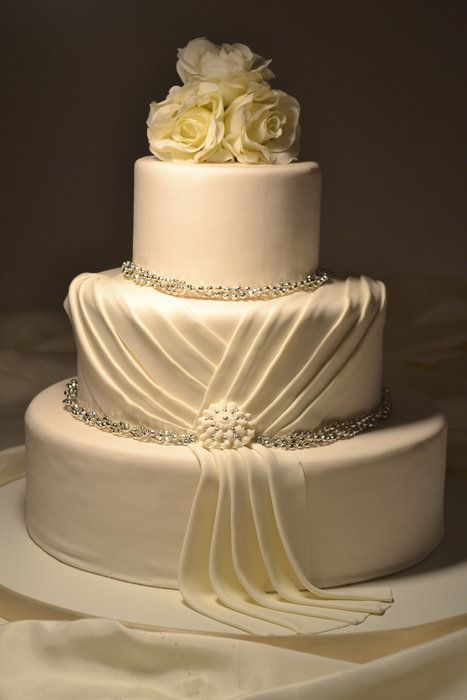 a three tiered wedding cake with white roses on top