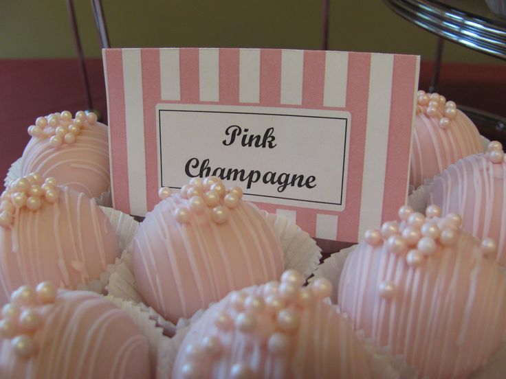 there are pink and white chocolates with pearls on them sitting in a pile next to a sign that says pink champagne