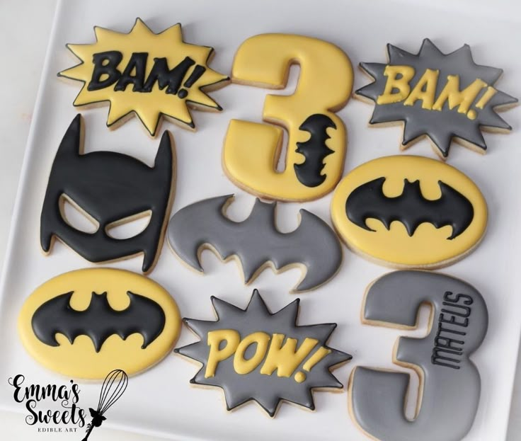 decorated cookies in the shape of batman's numbers and symbols on a white plate