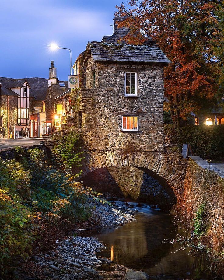 an old stone bridge over a small stream in the middle of town at night time