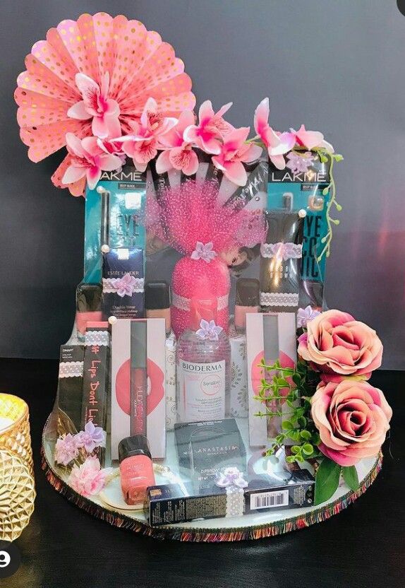 a table topped with pink flowers next to a candle and some books on top of it