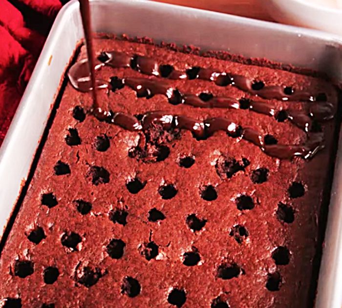 a pan filled with chocolate cake sitting on top of a wooden table next to a red towel