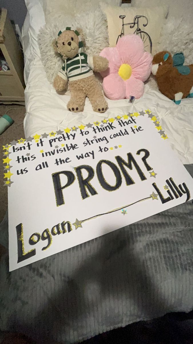 a teddy bear sitting on top of a bed next to a sign that says prom