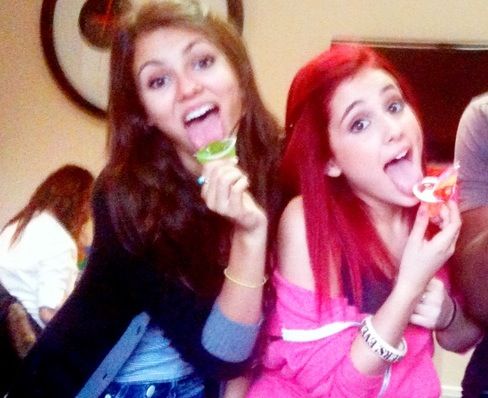 two young women eating food while standing next to each other