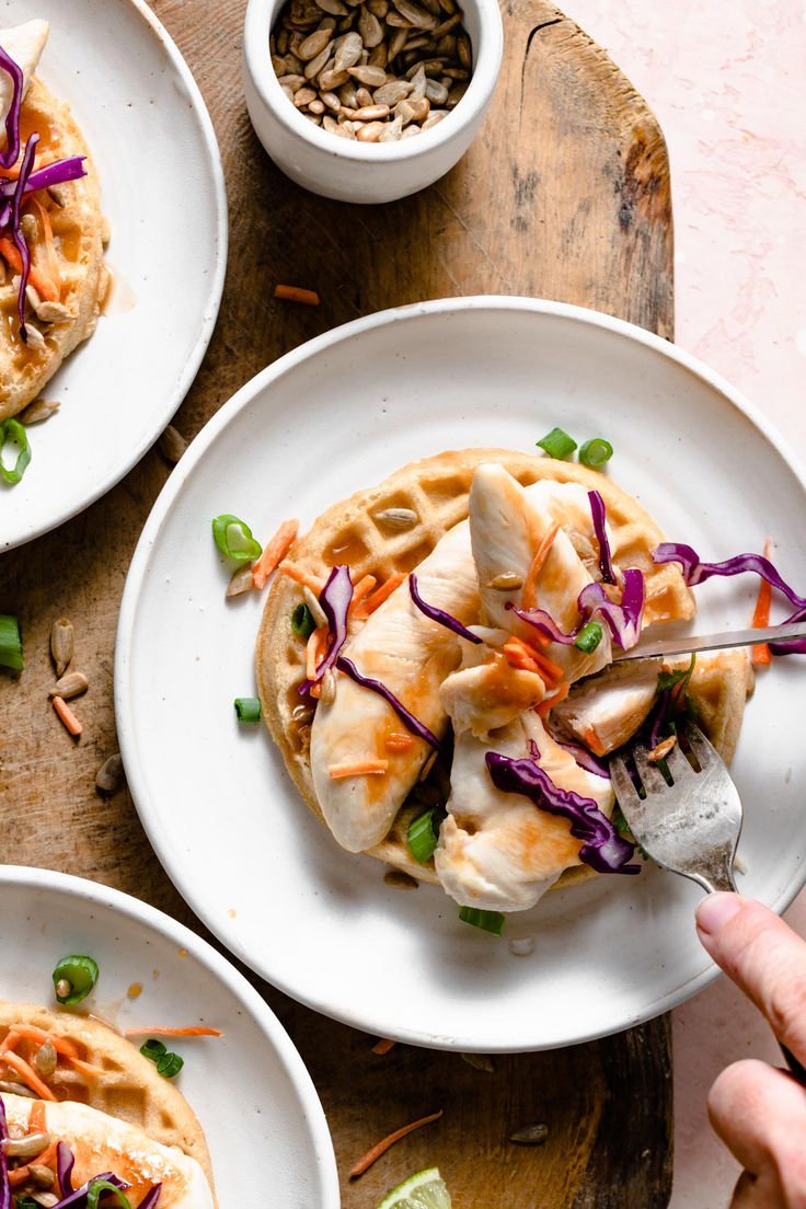 two white plates topped with food next to another plate filled with food on top of a wooden table