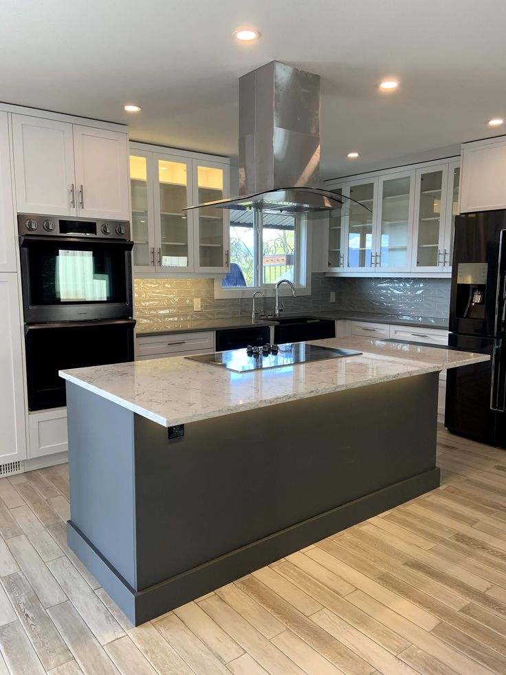 a large kitchen with an island in the middle and stainless steel appliances on both sides