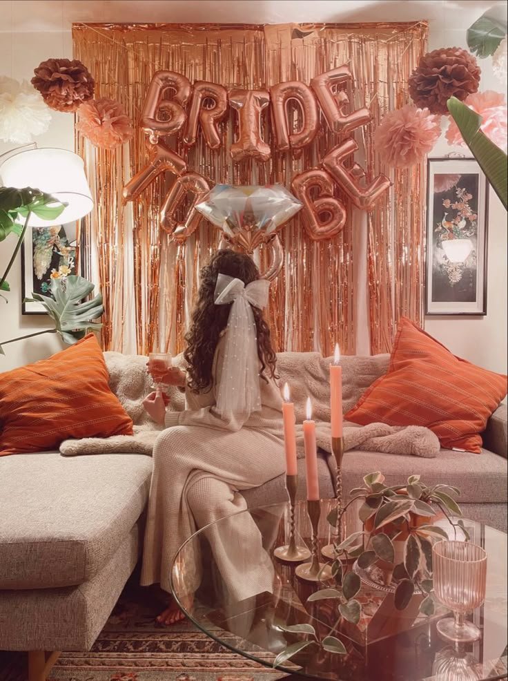 a woman sitting on a couch in front of a balloon arch with the word bride spelled out