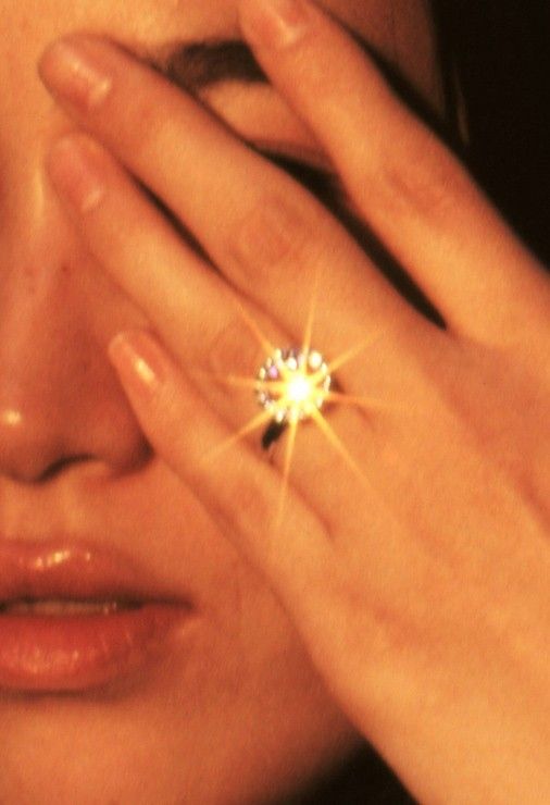 a woman holding her hand to her face with a diamond ring on it's finger