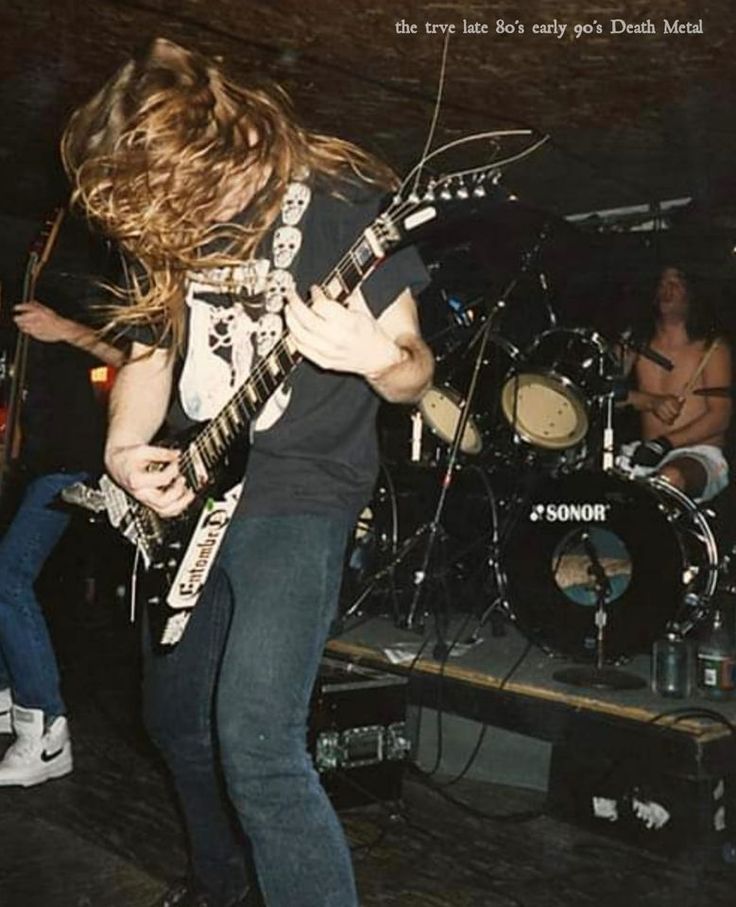 a man with long hair playing guitar on stage