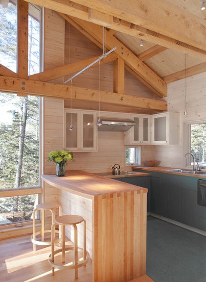 a kitchen with an island in the middle and wood floors on both sides, surrounded by windows