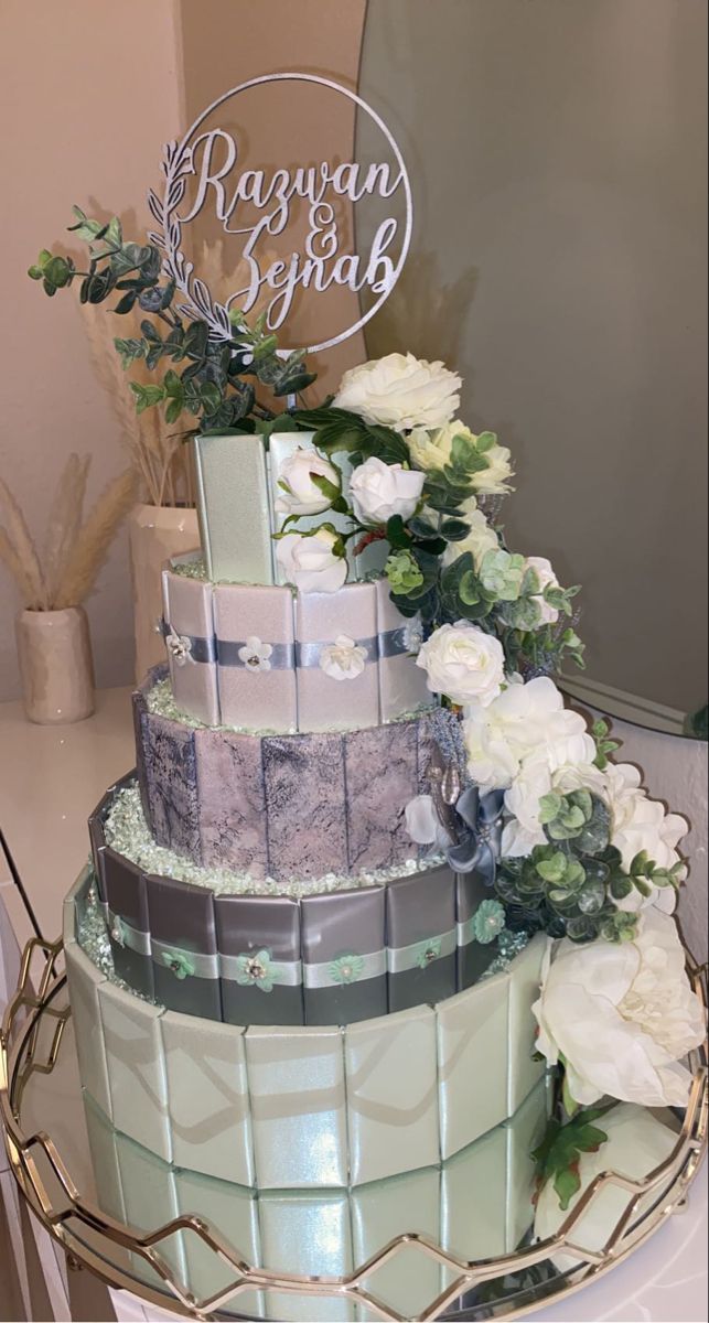 a three tiered cake with white flowers and greenery