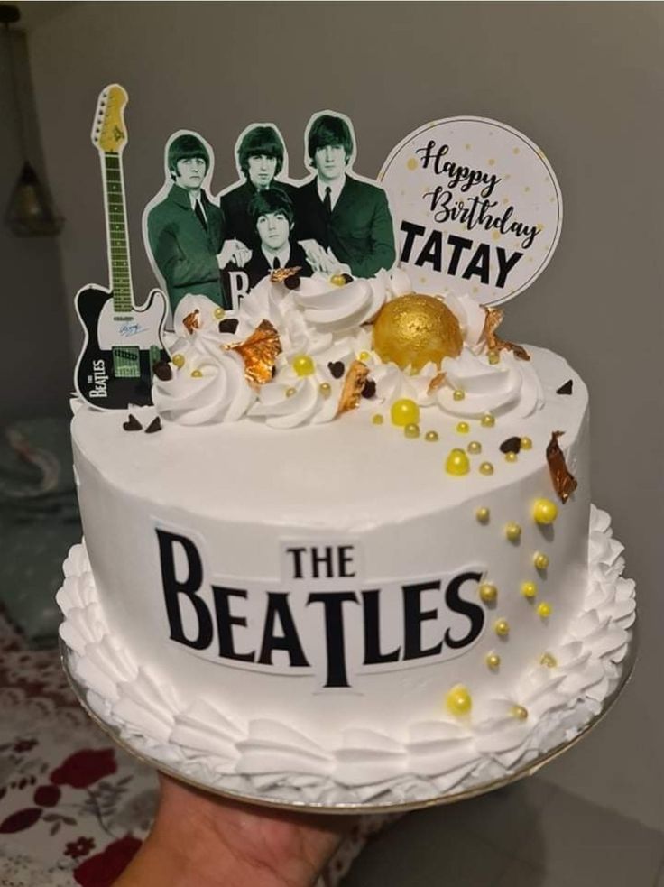 a cake with the beatles on it is being held up by someone's hand