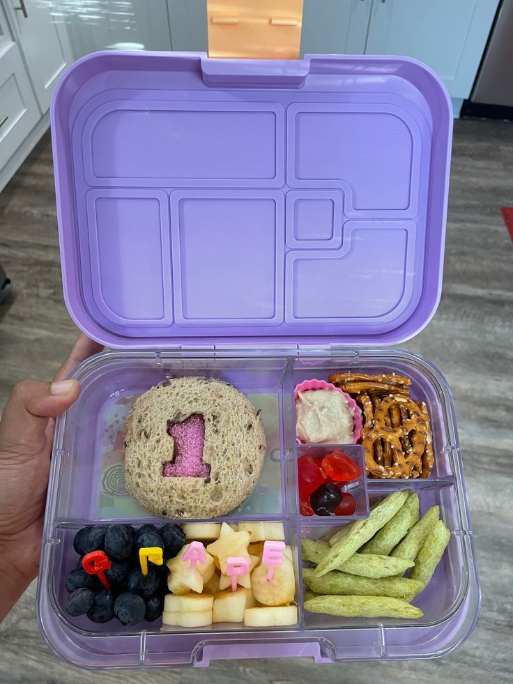 a person holding a purple lunch box filled with food