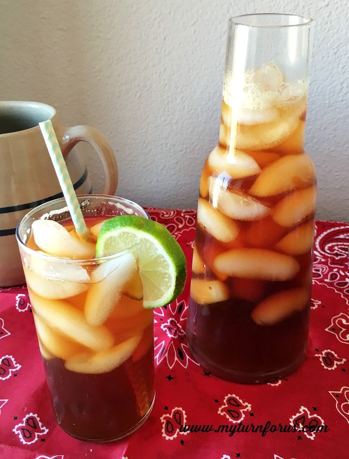 two glasses filled with drinks sitting on top of a table next to a pitcher and cup