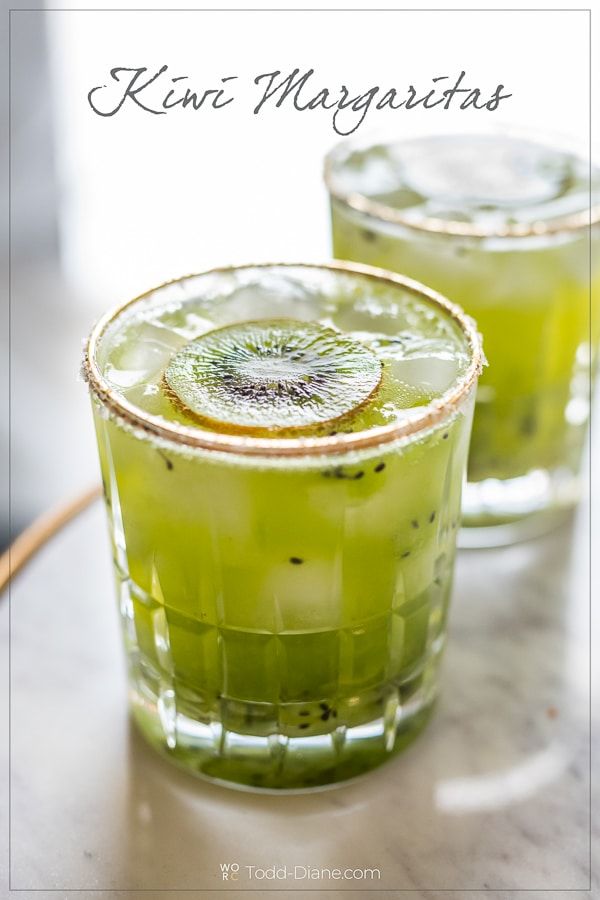 two glasses filled with kiwi margaritas sitting on top of a table