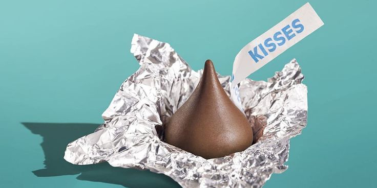 a piece of tin foil with a chocolate cone sticking out of it and a sign that says kisses