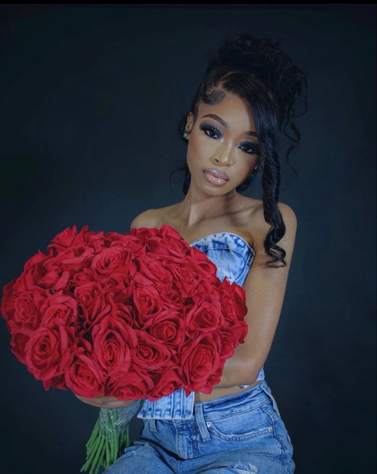 a woman holding a bunch of red roses in her hands and looking at the camera