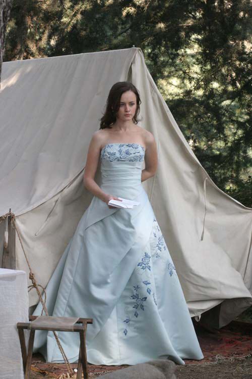 a woman in a blue dress standing next to a tent