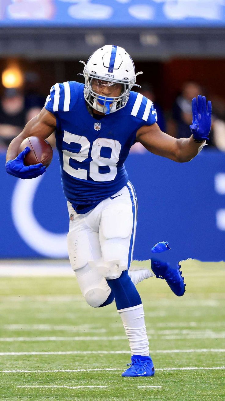 a football player is running with the ball in his hand and wearing blue gloves on