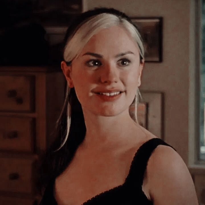 a woman in a black dress smiling at the camera