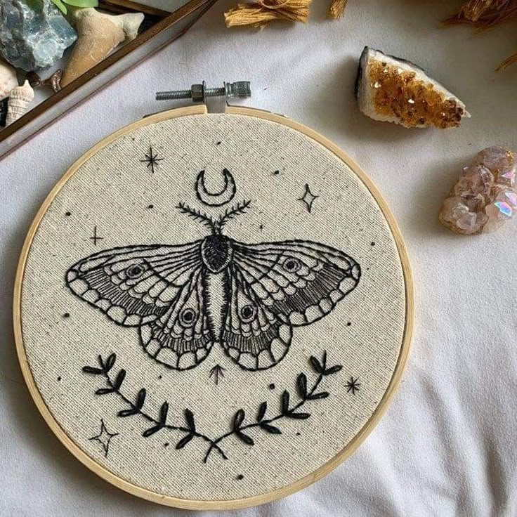 a close up of a embroidery on a table with rocks and plants in the background