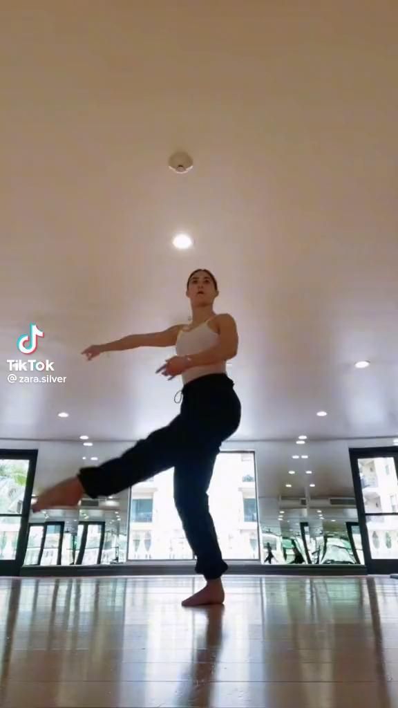 a woman standing on one leg in the middle of a dance floor