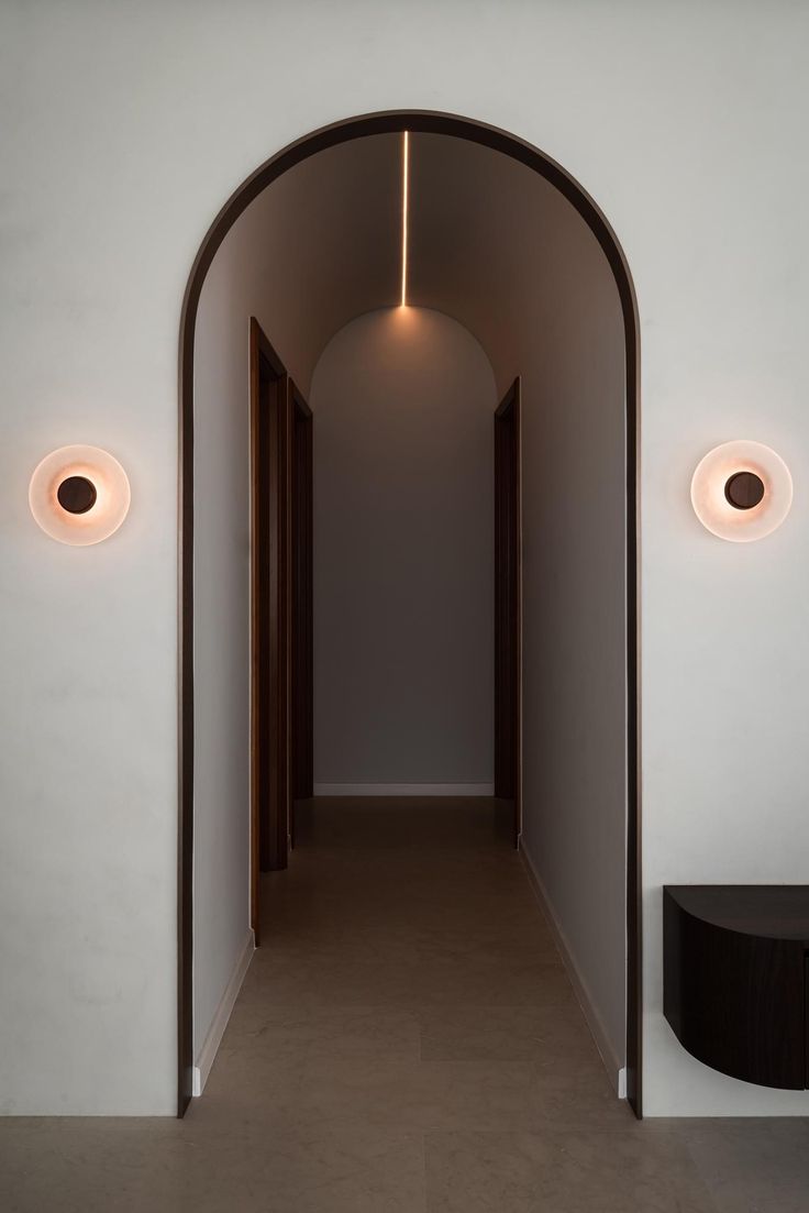 an arched hallway with two circular lights on the wall