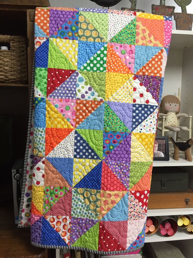 a multicolored quilt is hanging on a rack in a room with other items