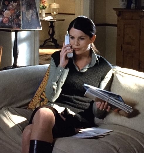 a woman sitting on a couch talking on a cell phone and holding a folder in her hand