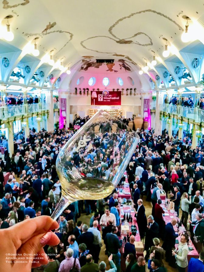 a person holding up a wine glass in front of a large room full of people