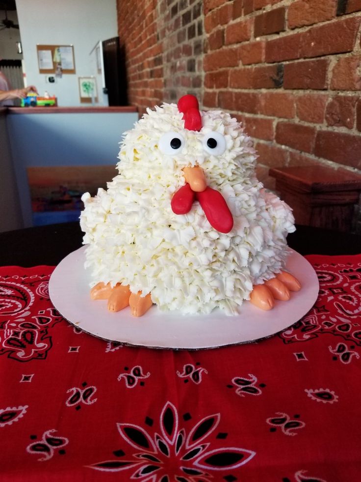 a cake made to look like a chicken sitting on top of a red table cloth