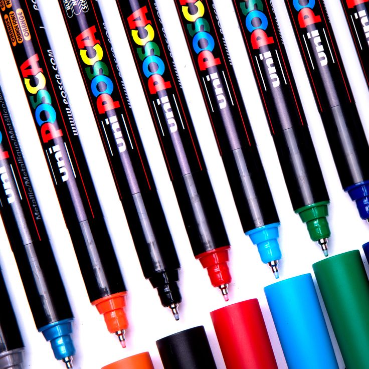 many different colored pens lined up next to each other on a white surface with black ink