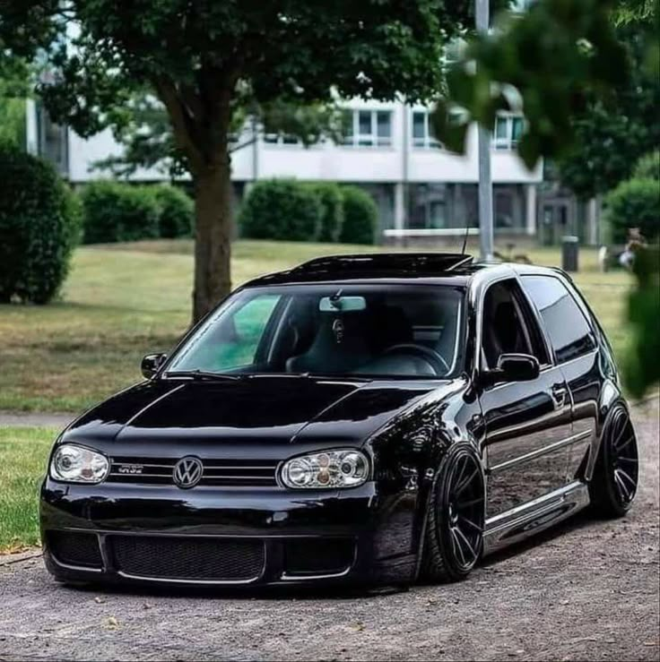 a black vw golf wagon parked on the side of a road next to trees