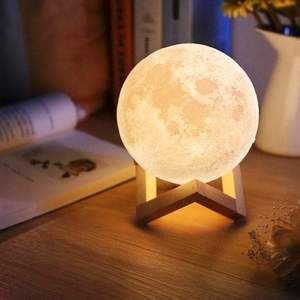 the moon lamp is sitting on top of a table next to a book and flowers