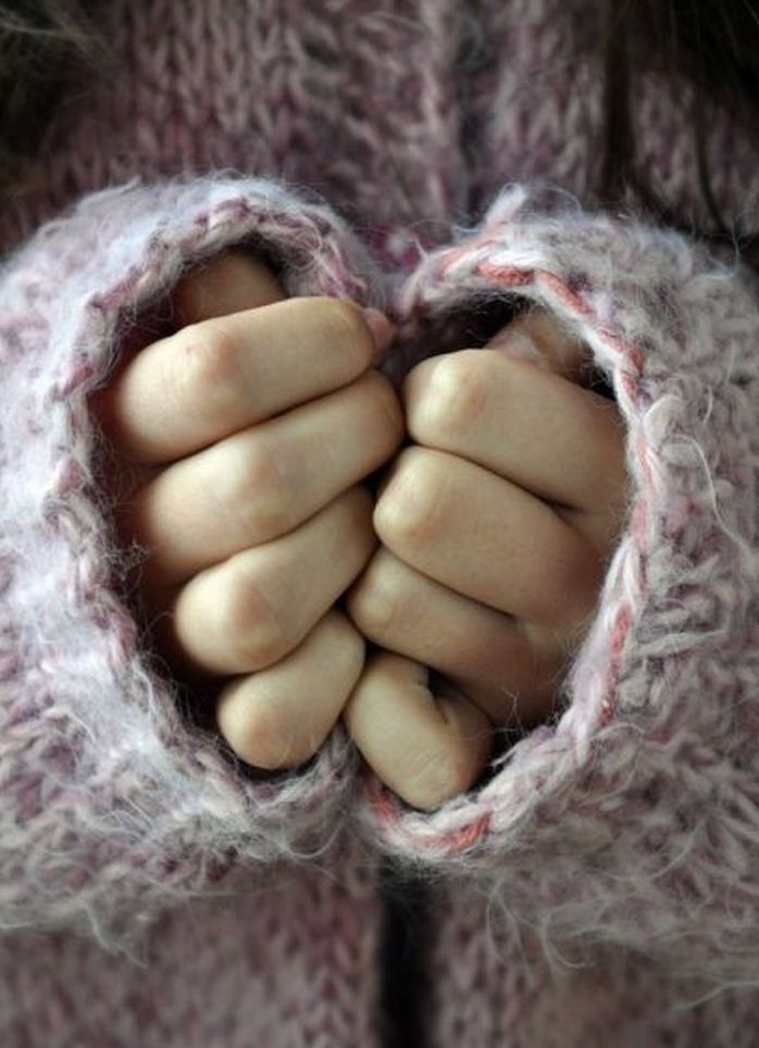 a close up of a person wearing a knitted sweater with their hands in the center