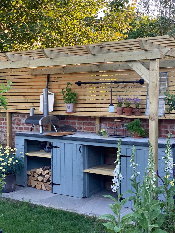 an outdoor kitchen is built into the side of a brick building with potted plants