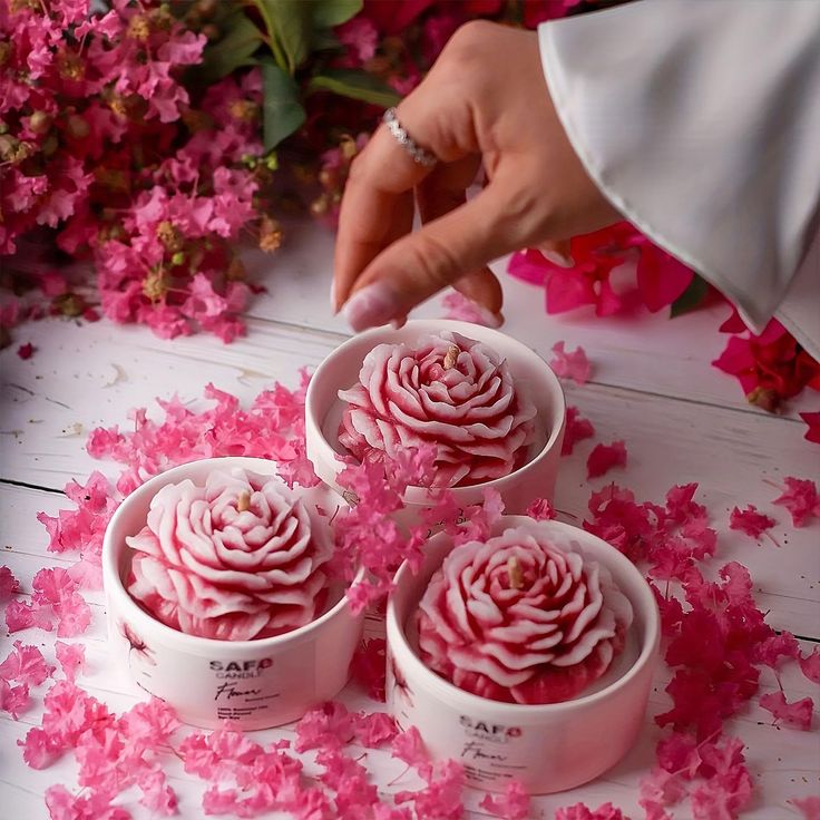 pink flowers are being placed in small white containers