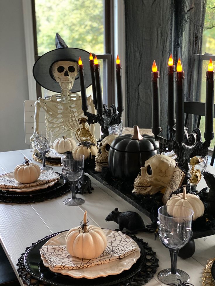 a dining room table decorated for halloween with skeletons and pumpkins on the place settings