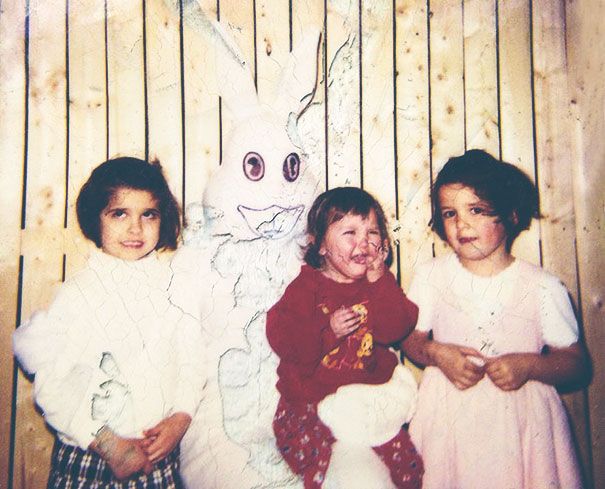 three girls standing next to each other in front of a wooden wall with a white bunny