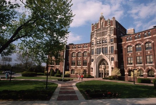 a large brick building sitting on top of a lush green field next to a tree