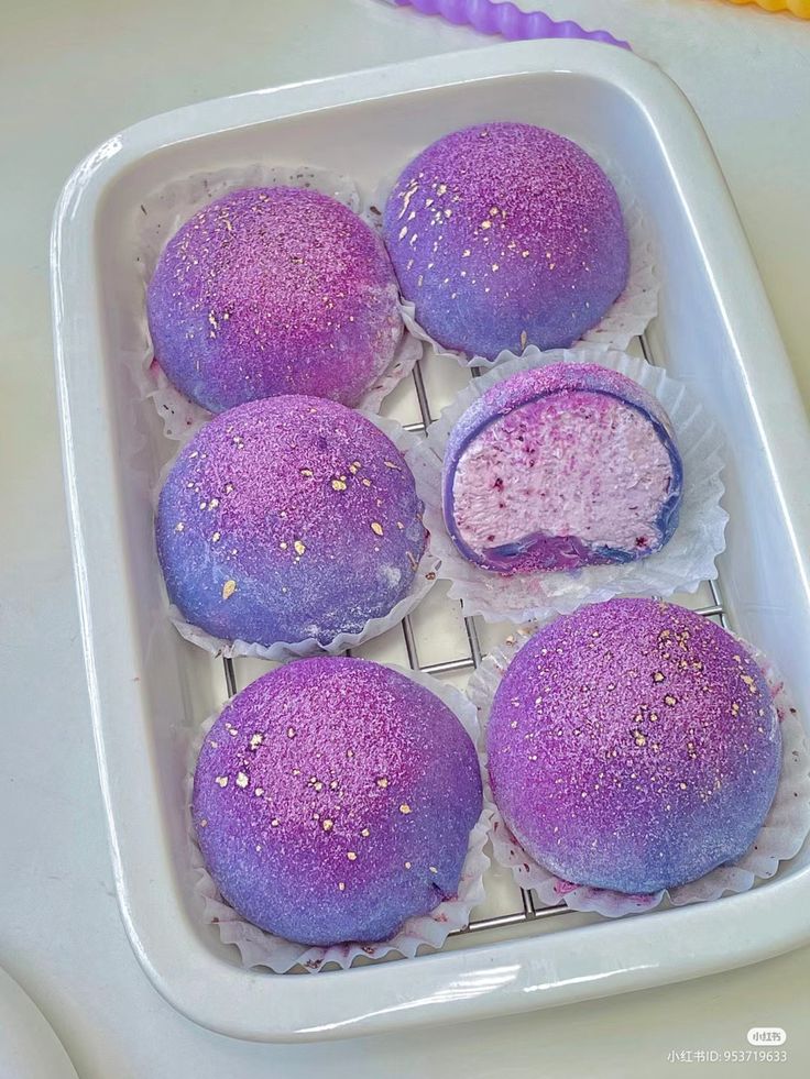 there are some purple cakes in the tray