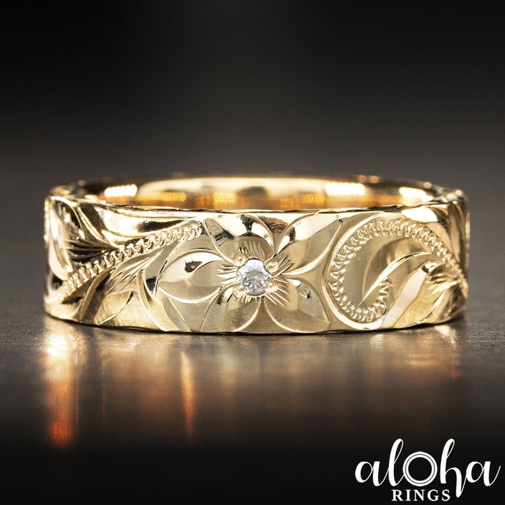 a yellow gold wedding band with an intricate floral design and a diamond in the center